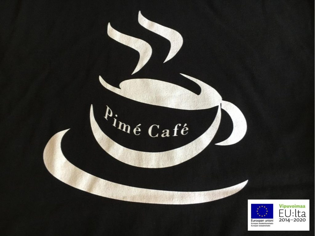 Kuvassa on mustalla pohjalla vaaleat kahvikupin ääriviivat ja teksti ”Pimé Café”. Alanurkassa on EU:n lippulogo.